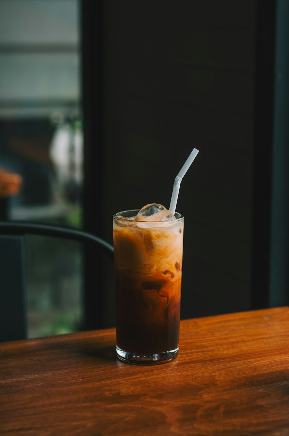 a glass of iced coffee sitting on top of a wooden table