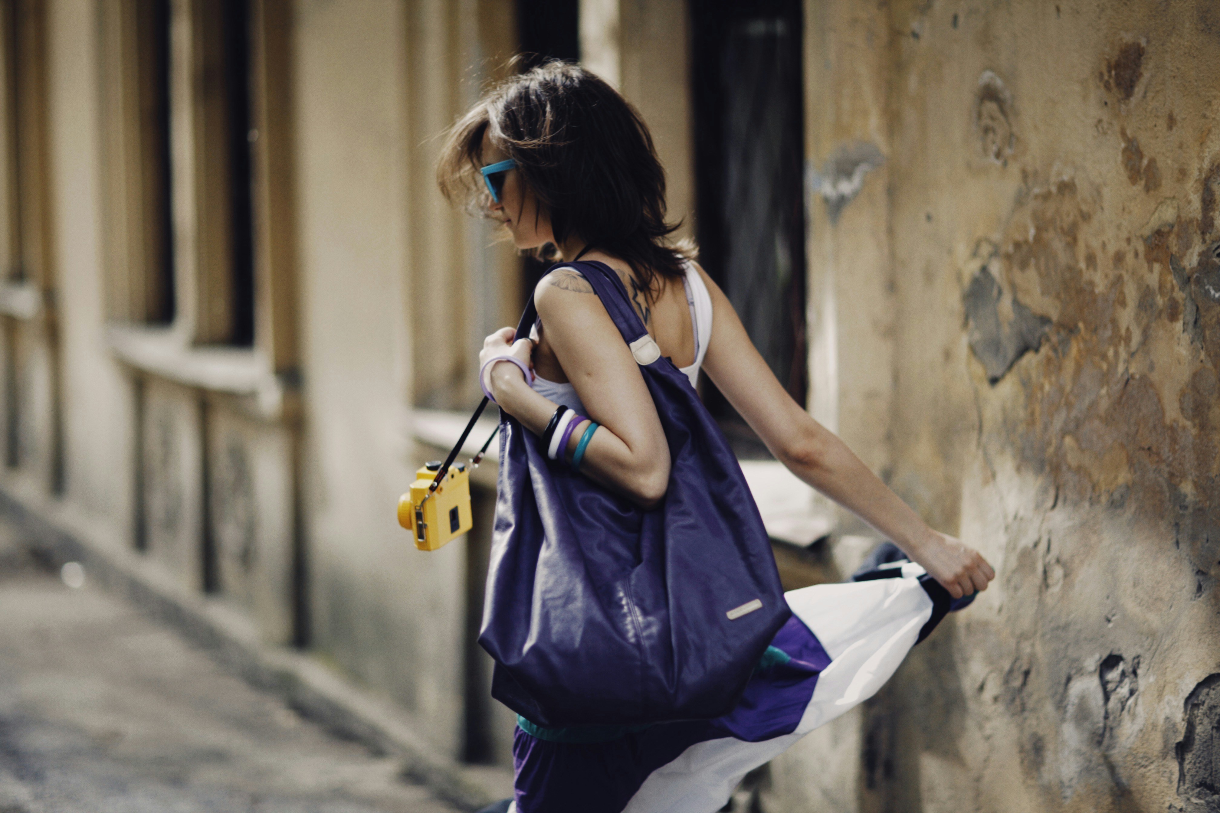 a woman walking down a street carrying a purple bag