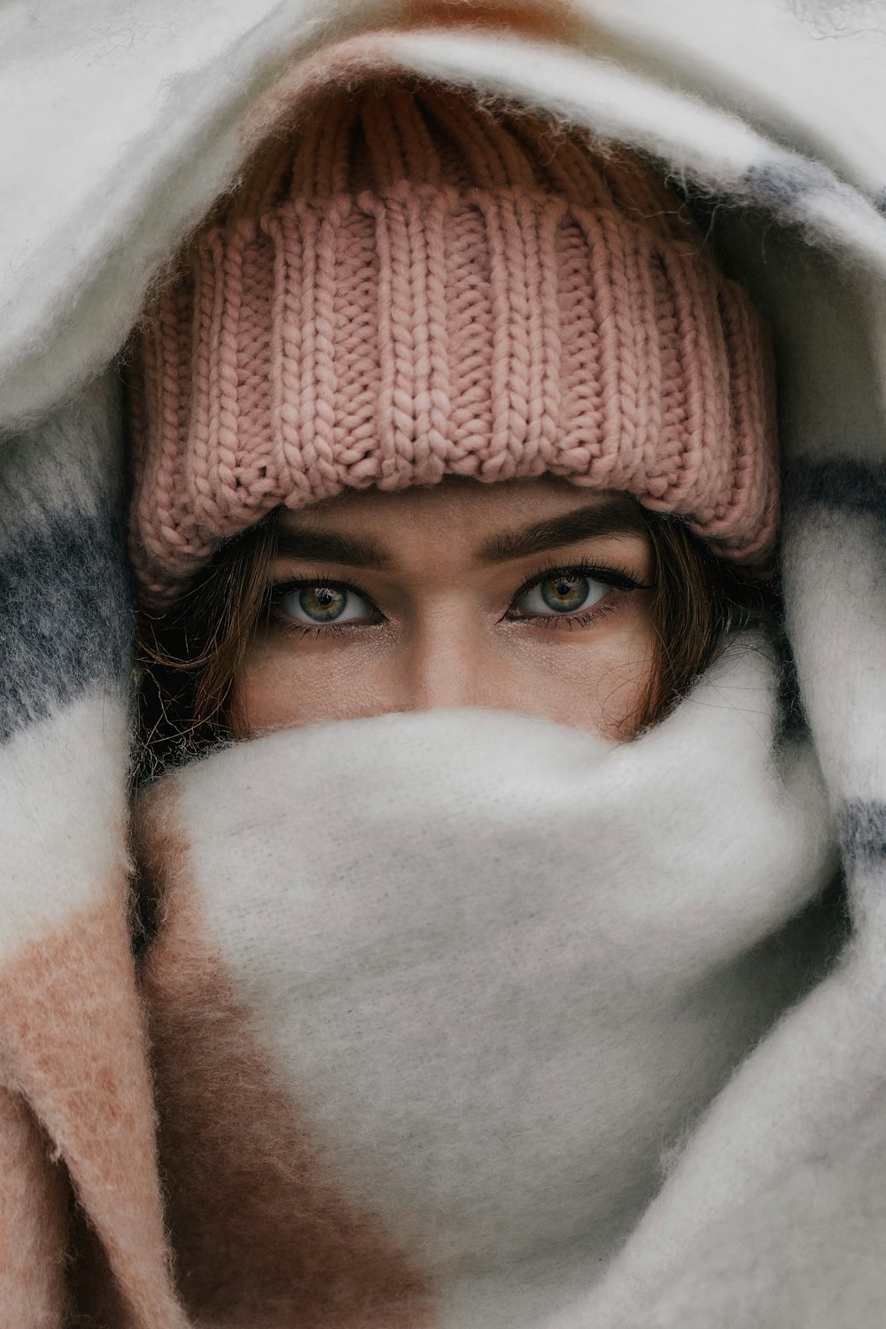 a woman with blue eyes hiding under a blanket