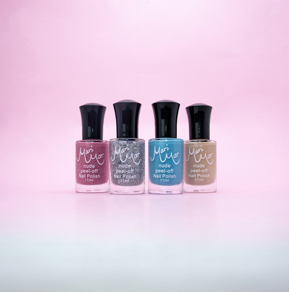 three bottles of nail polish on a pink background