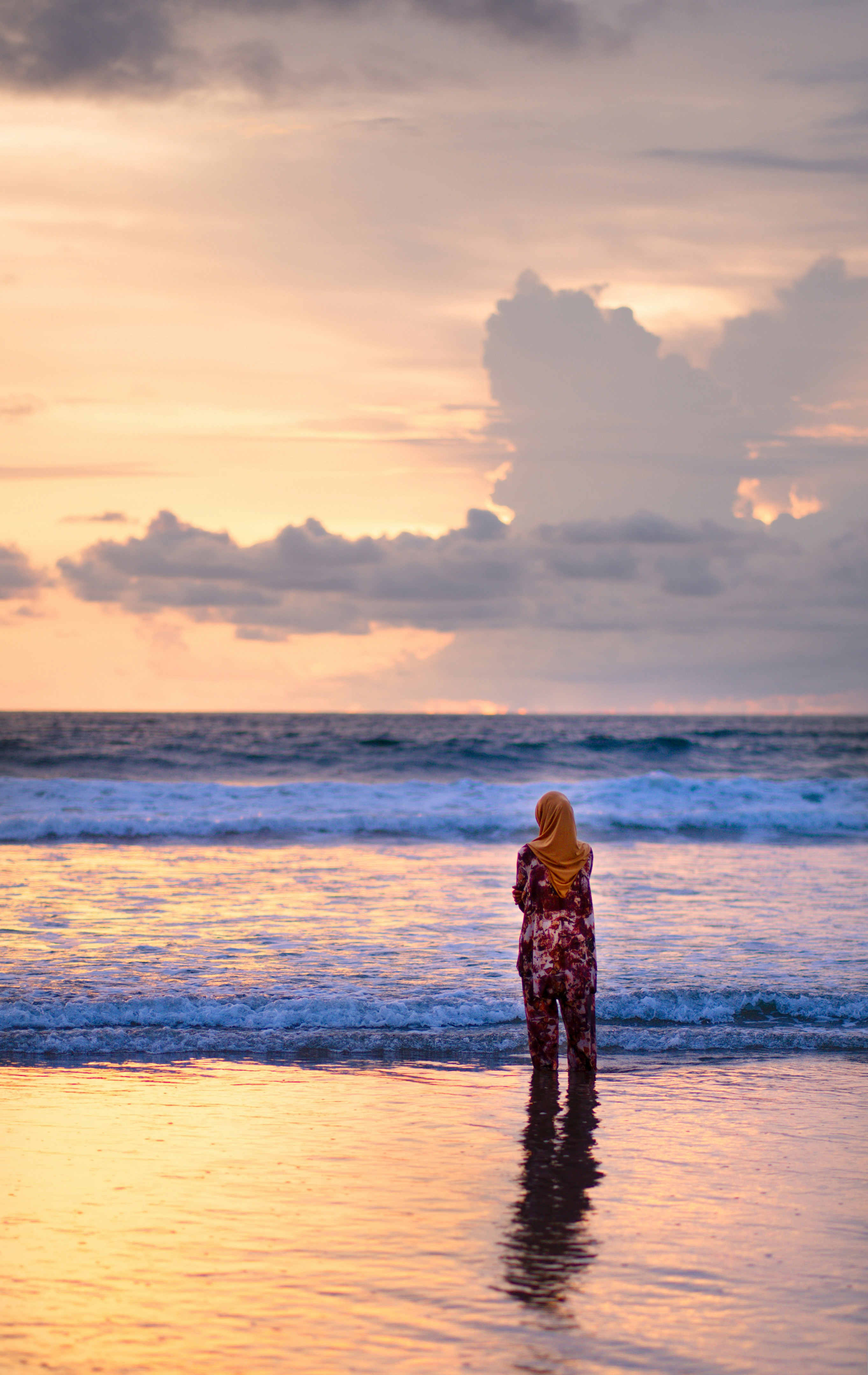 a woman standing on a beach next to the ocean