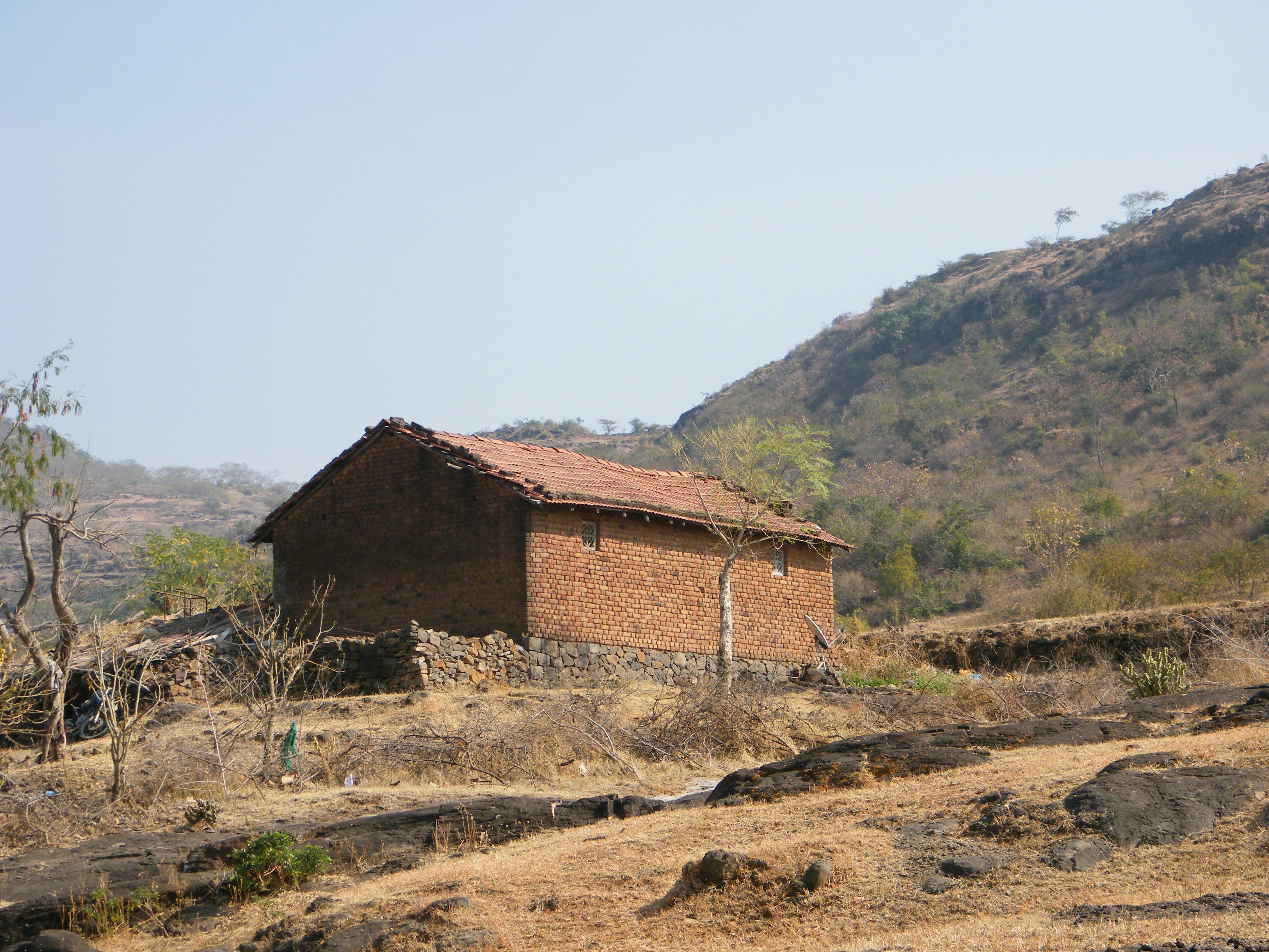 a small brick building sitting on top of a dry grass field