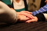 a group of people holding hands on top of a bed