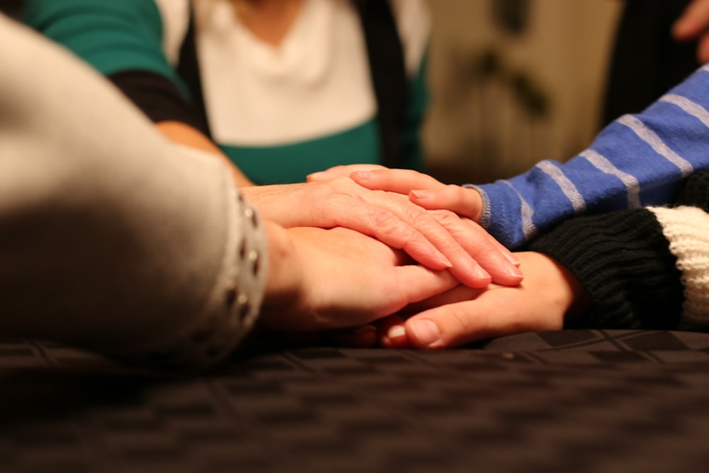 a group of people holding hands on top of a bed