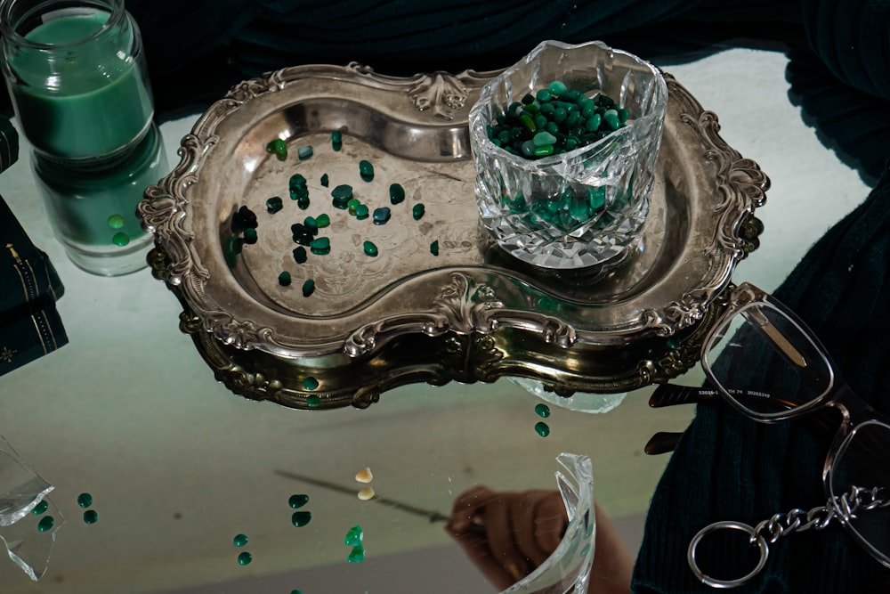 a silver tray with green beads on it