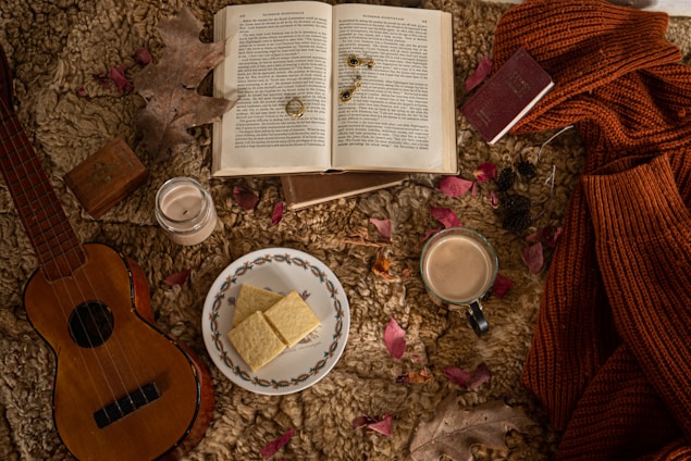 A cozy flat lay of a journal, a cup of herbal tea, scented candles, and wellness books on a soft blanket.