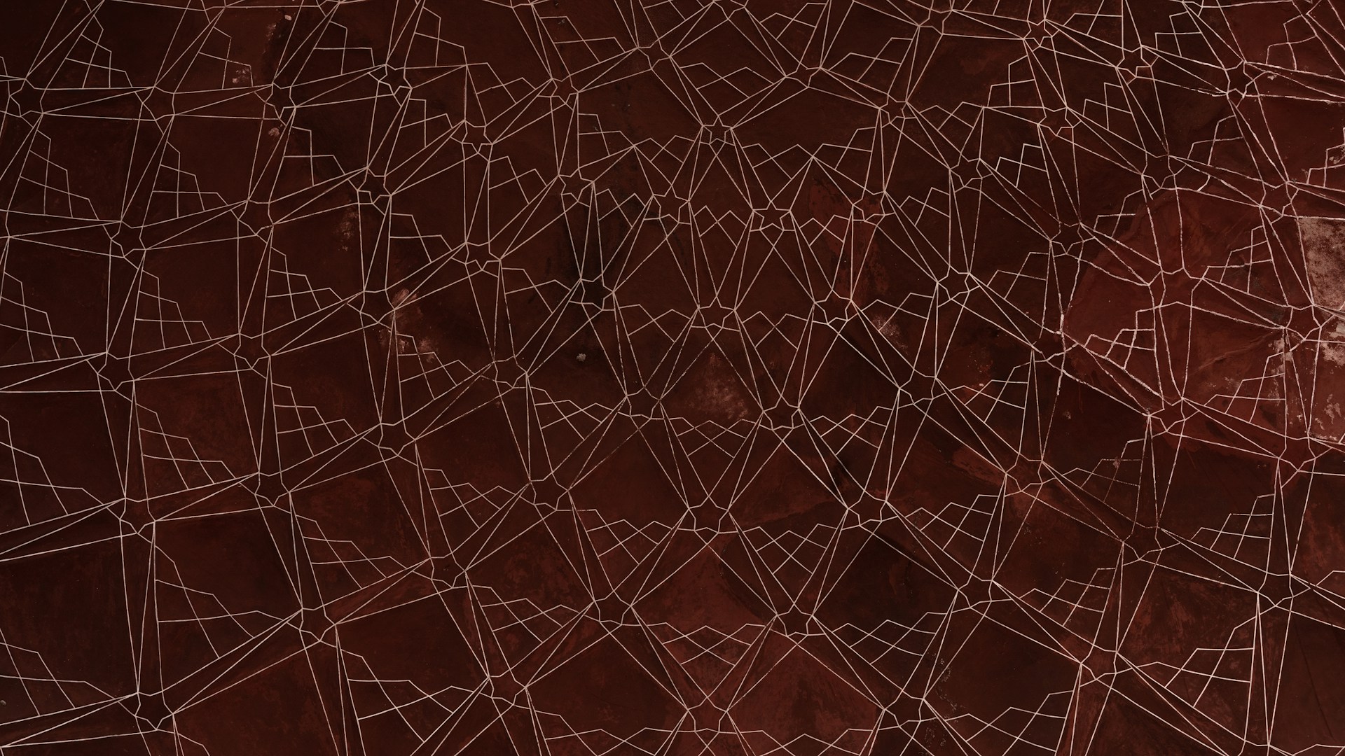 Intricate geometric patterns in a symmetrical design formed by white lines against a dark brown background. The pattern creates shapes reminiscent of abstract and architectural elements, providing a sense of depth and complexity.