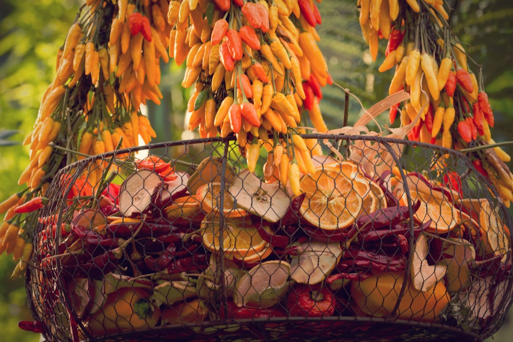 a basket full of oranges and bananas hanging from a tree