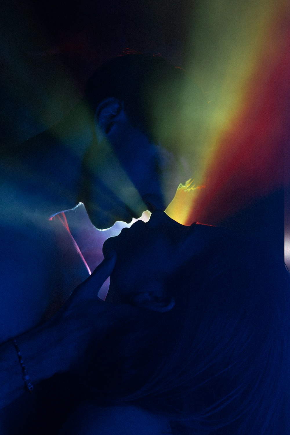 a person with their face obscured by a rainbow colored light