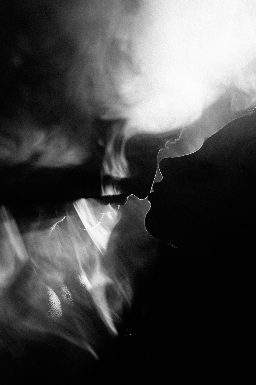 une photo en noir et blanc d’une personne fumant une cigarette