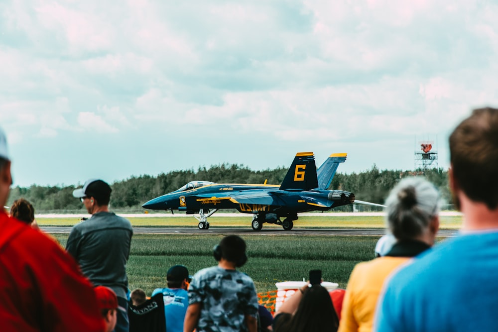 a group of people watching a fighter jet on a runway
