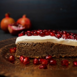a piece of cake with white frosting and pomegranates