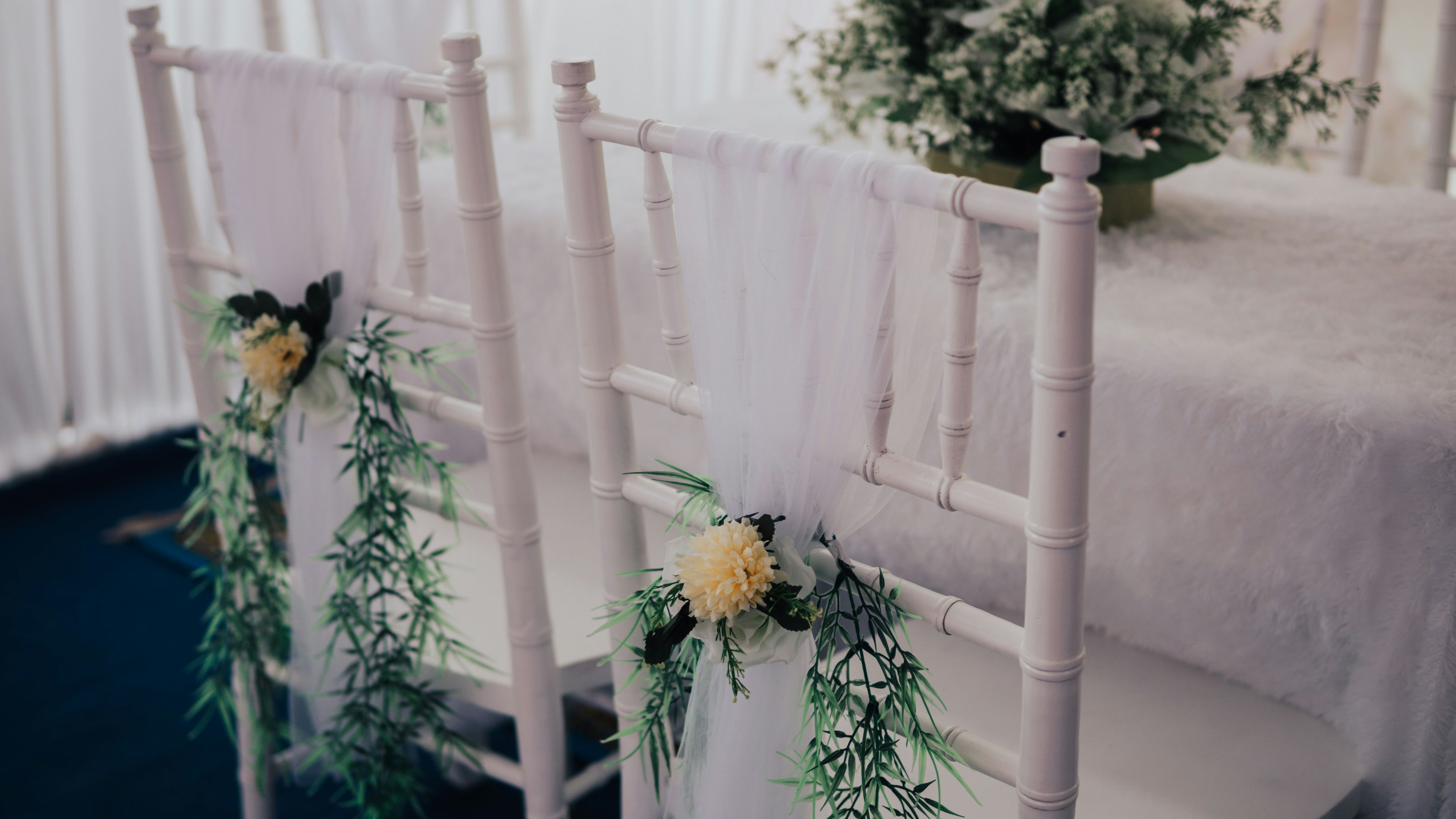 a row of white chairs with flowers on them