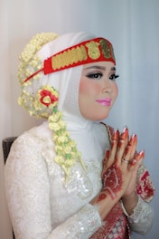 a woman in a white wedding dress with a red and gold head piece