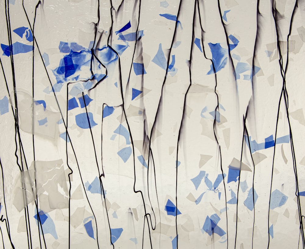 uma pintura de folhas azuis e brancas em uma parede branca