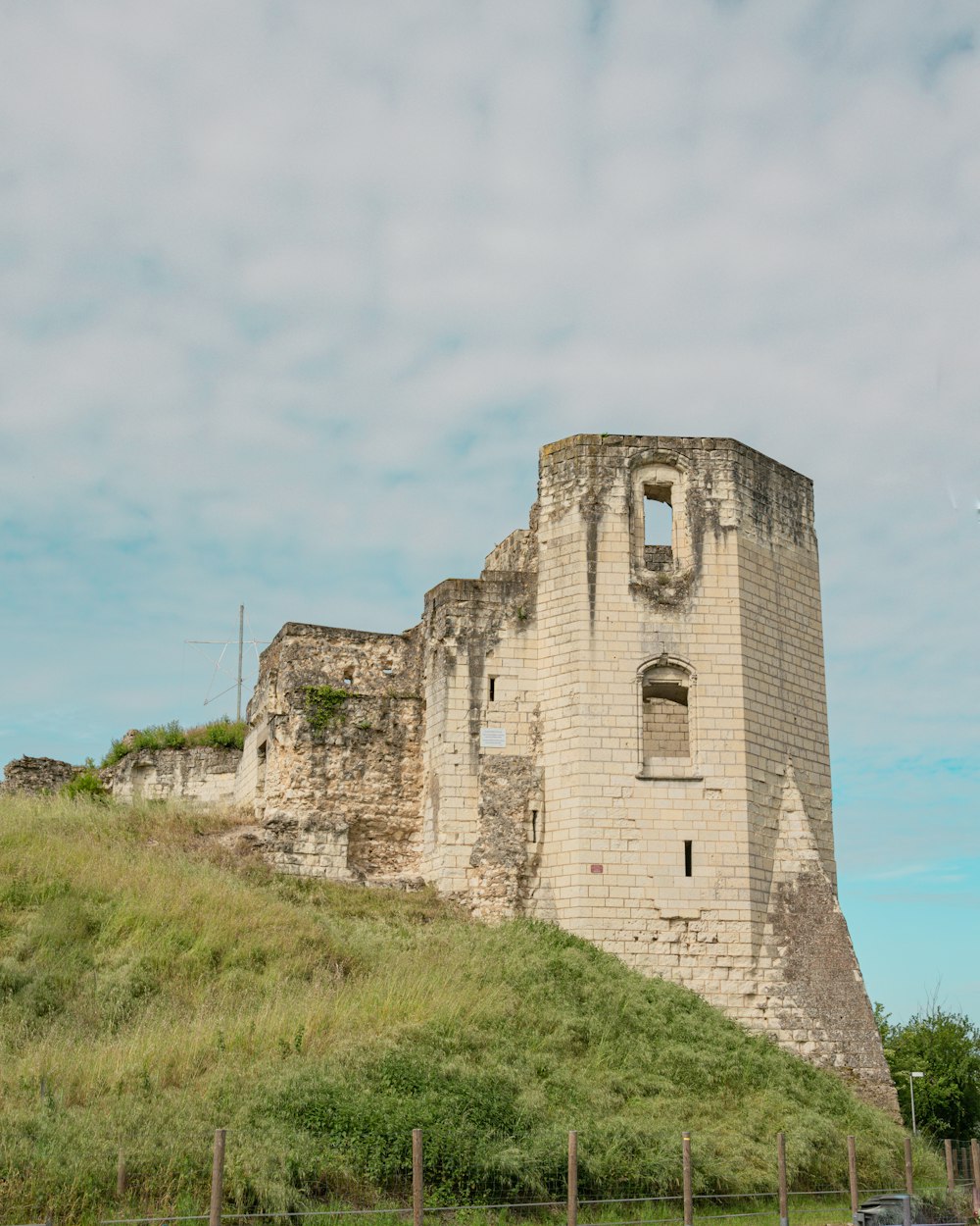 a large stone building sitting on top of a lush green hillside