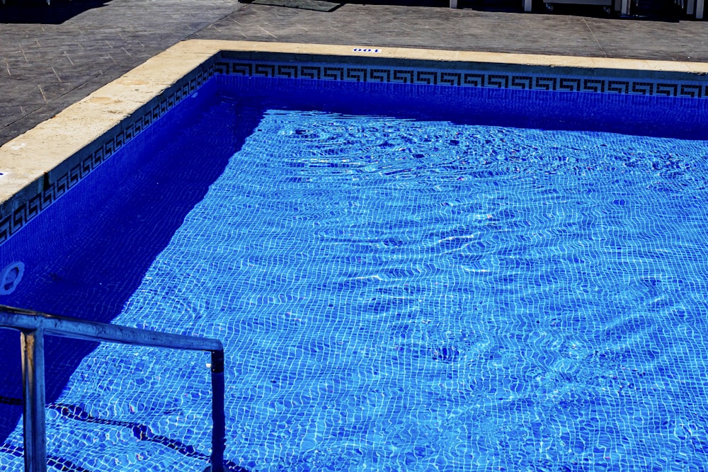 a blue swimming pool with a metal hand rail