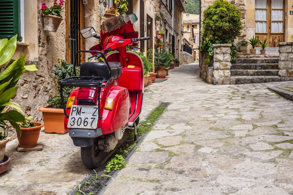 a red scooter parked on a cobblestone street