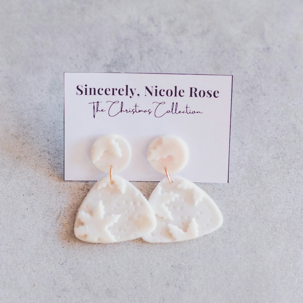 a pair of white earrings sitting on top of a table