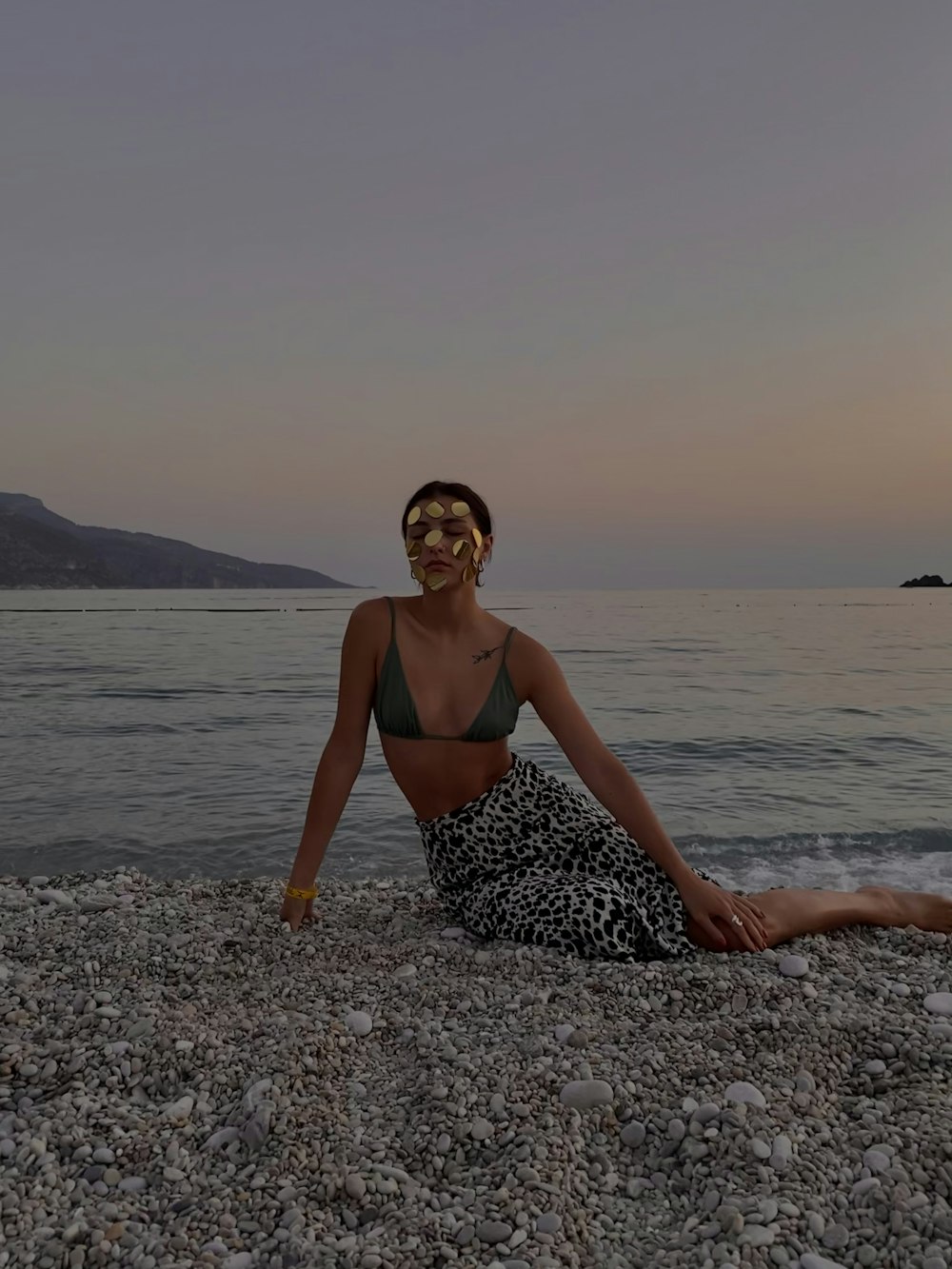 uma mulher sentada em uma praia ao lado do oceano