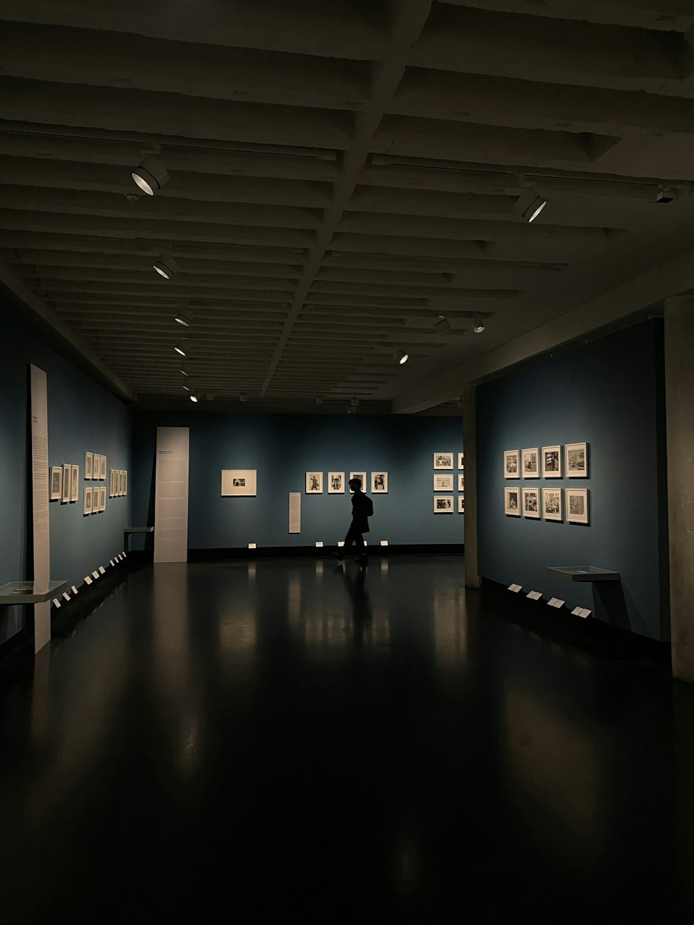 a person standing in a dark room with pictures on the wall