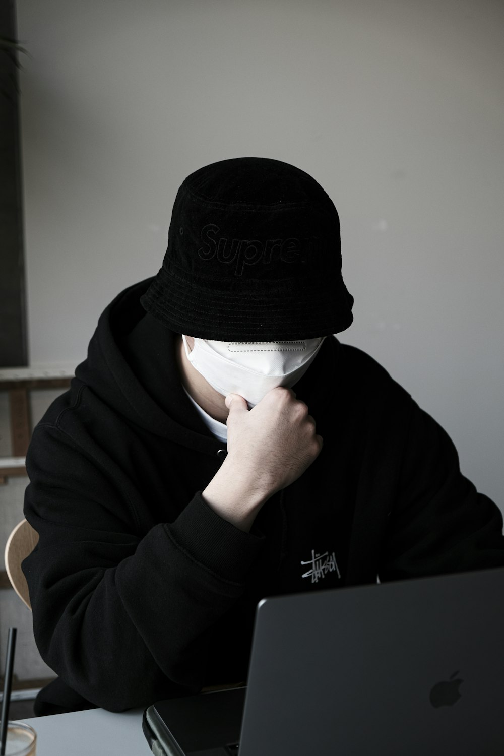 a person wearing a black hat and covering his face with a white mask