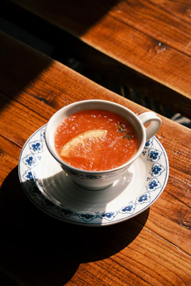 a bowl of soup on a saucer on a wooden table