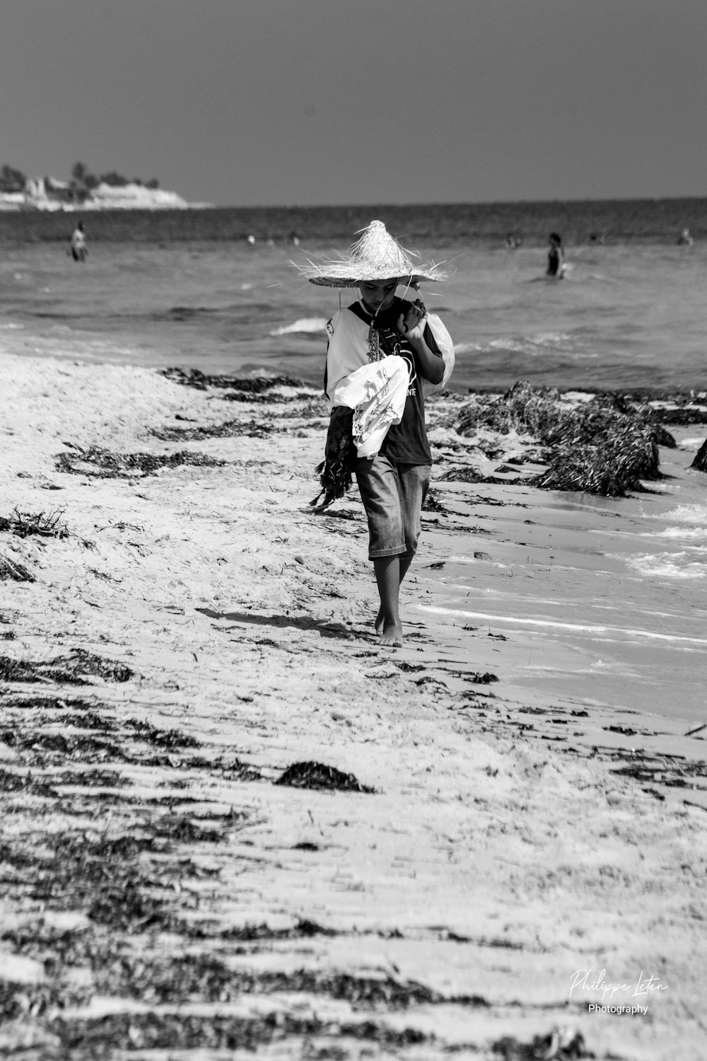 a person walking on a beach with a hat on