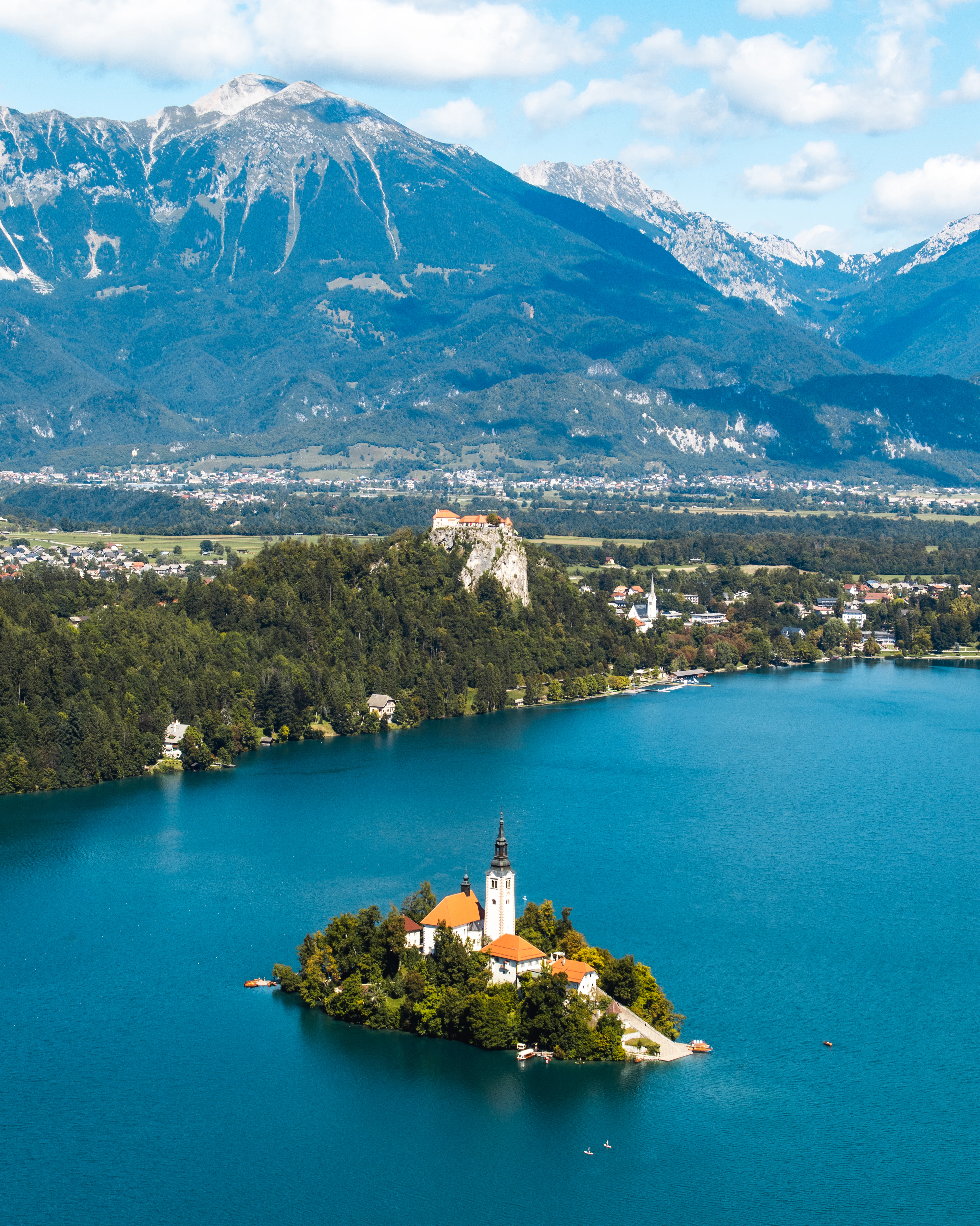 Lake Bled from above, the island church in the middle of the water with the castle on the rock beyond