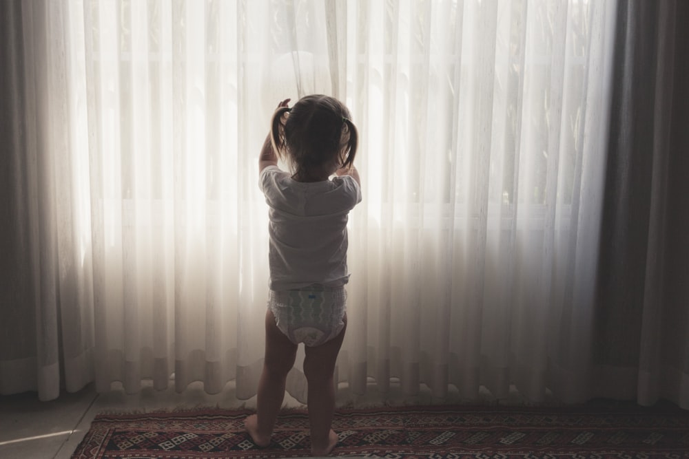 a little girl standing in front of a window