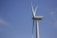 A large wind turbine stands against a clear blue sky, showcasing its long, sleek blades. The structure is modern and designed for harnessing wind energy.