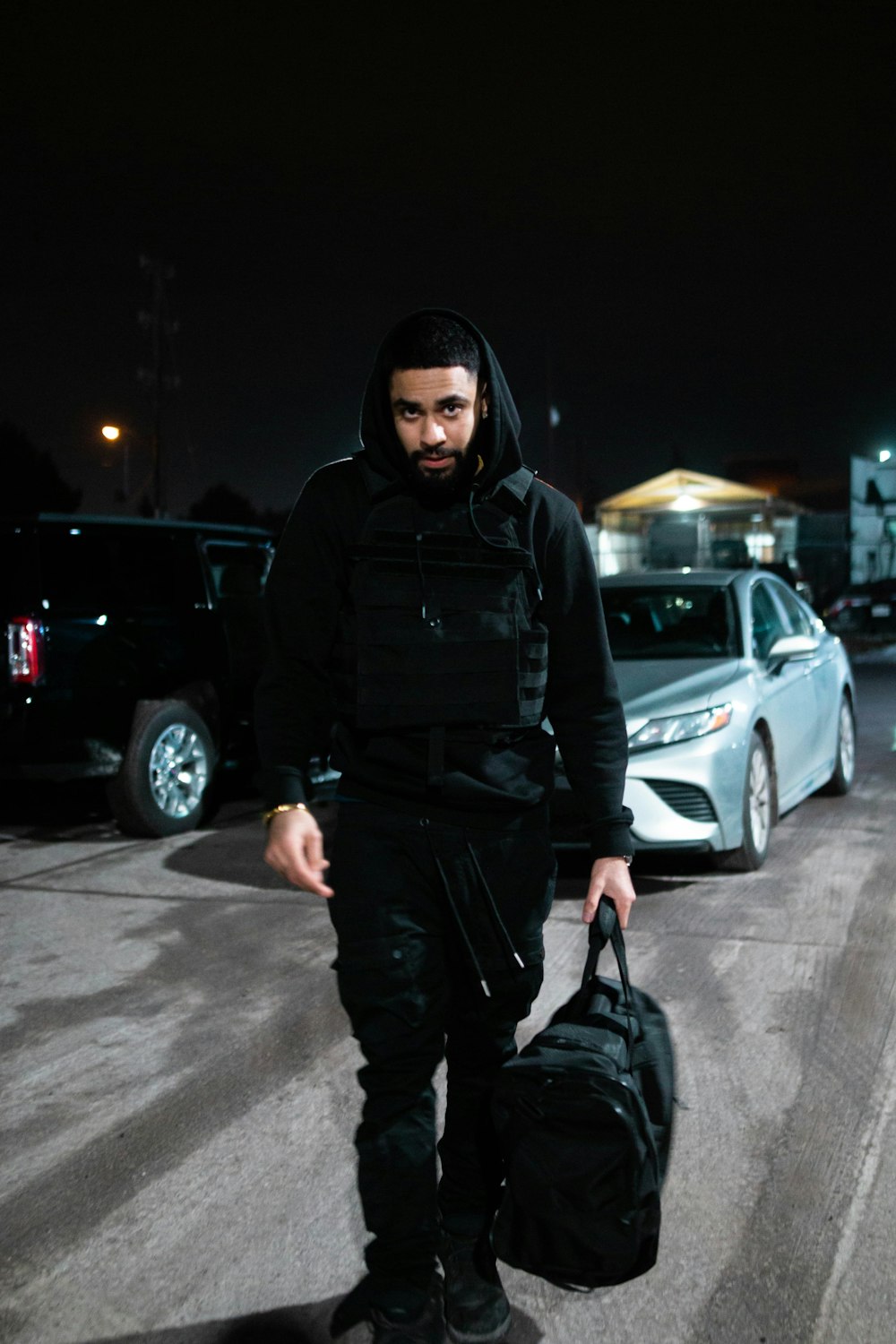 a man in a black hoodie carrying a black bag