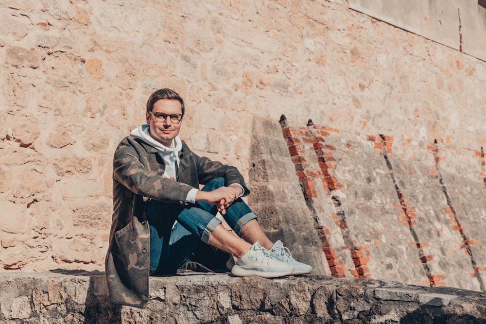 a man sitting on top of a stone wall