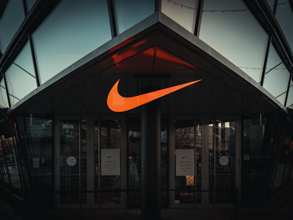 A large orange nike logo on the side of a building photo – Free Deutschland  Image on Unsplash