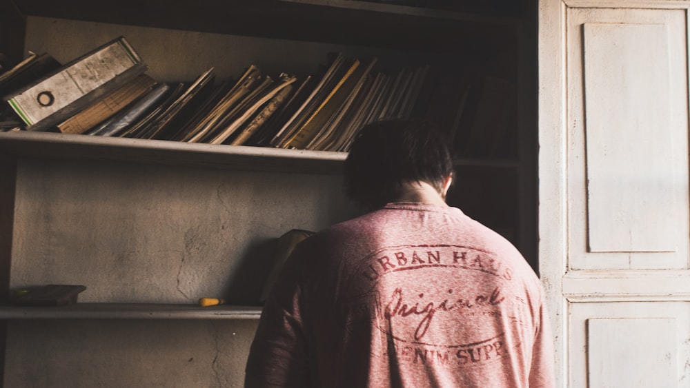 a man standing in front of a book shelf filled with books