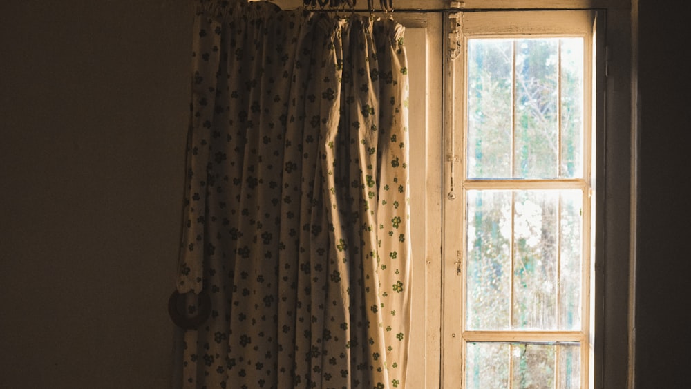a window with curtains and a cat sitting on the window sill