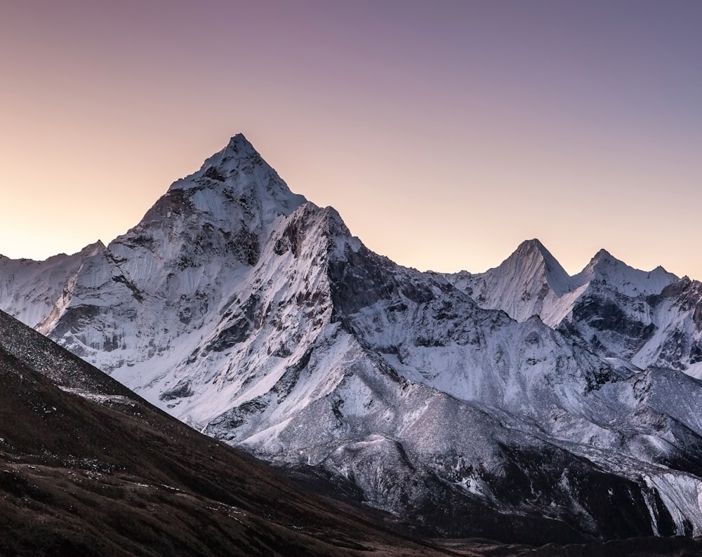 a mountain range covered in snow at sunset