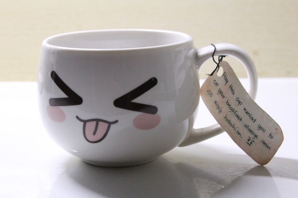 a white coffee cup with a face drawn on it