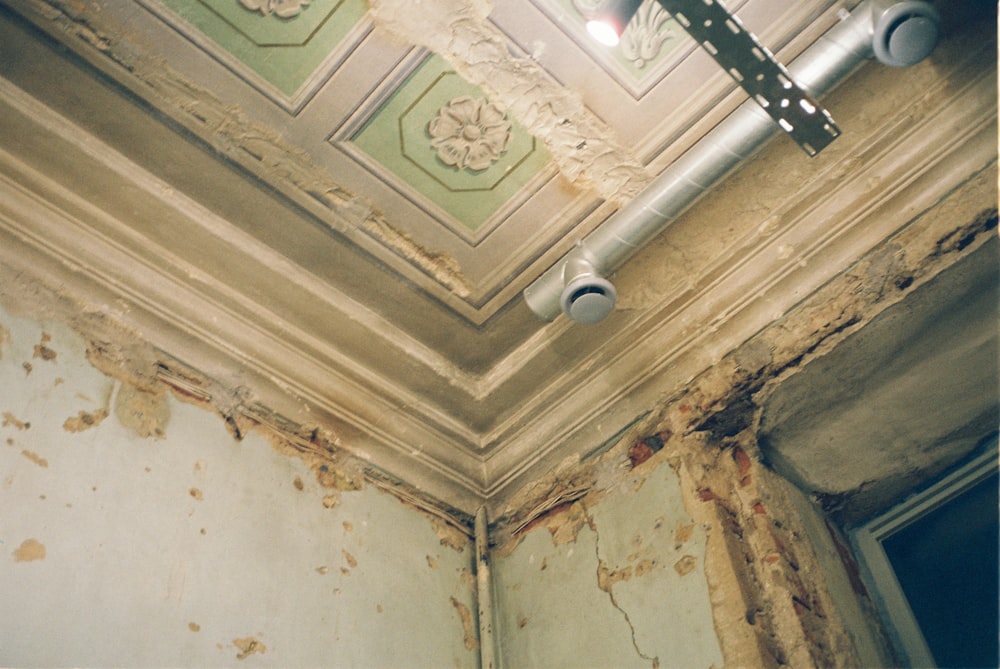 o teto de uma sala degradada com tinta descascada