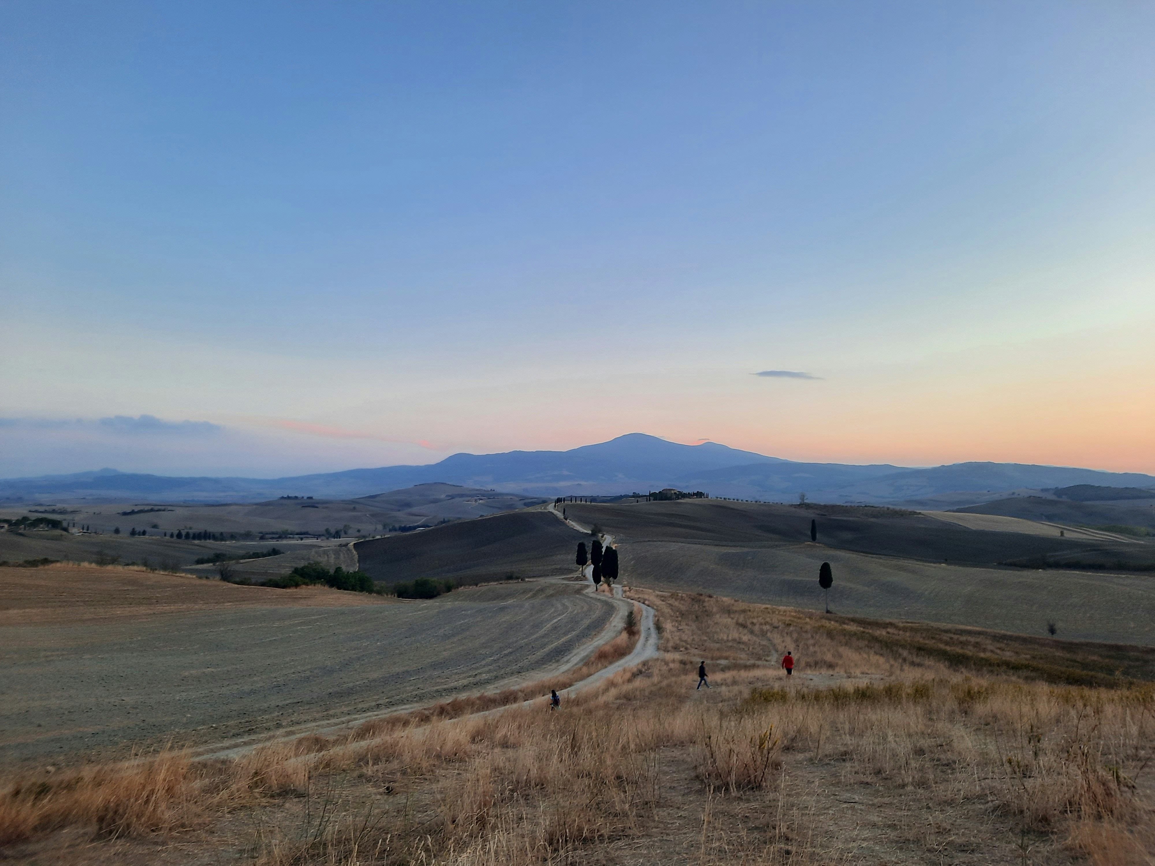 A couple of people walking down a dirt road