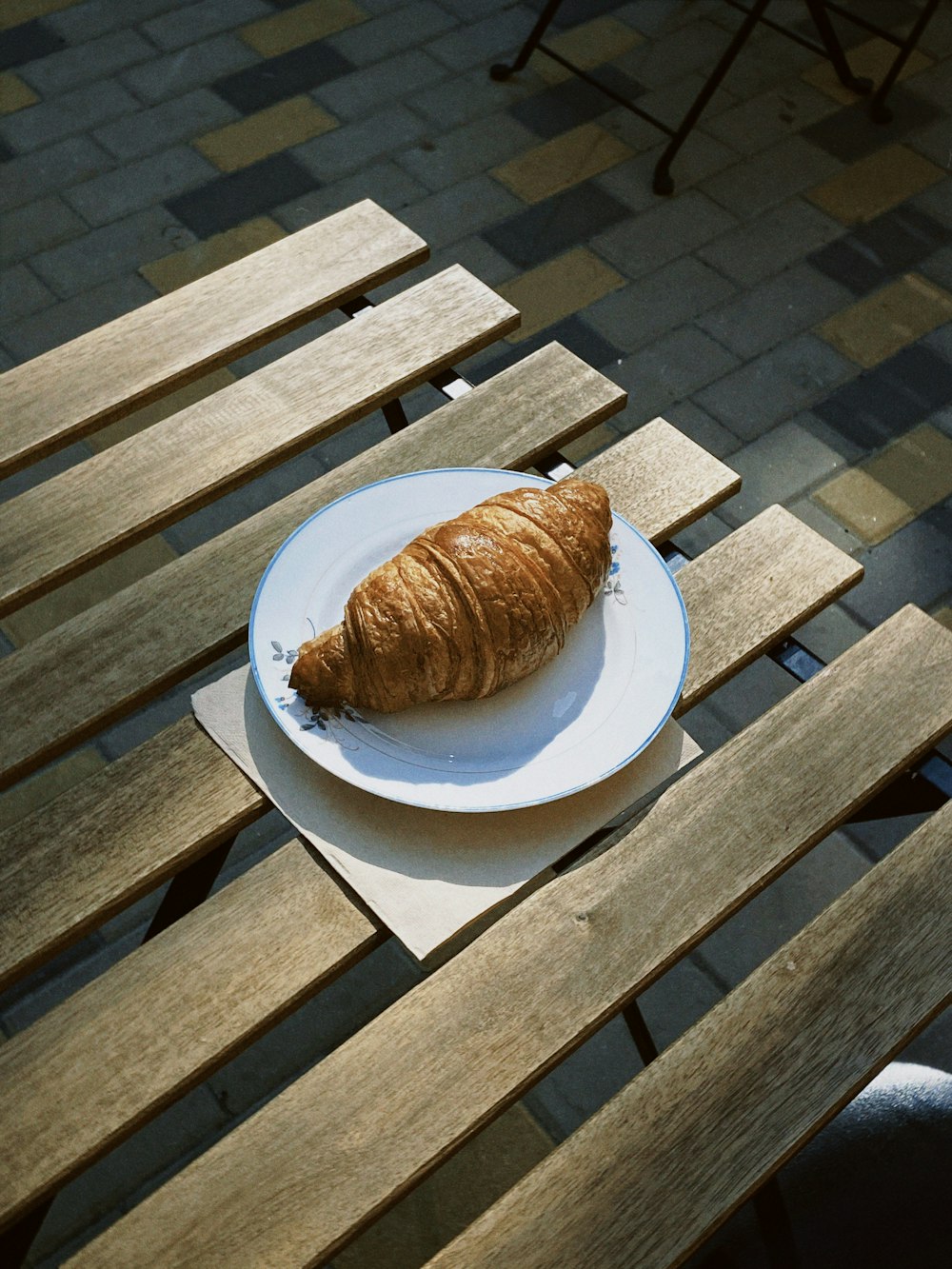 a croissant sitting on a plate on a wooden table