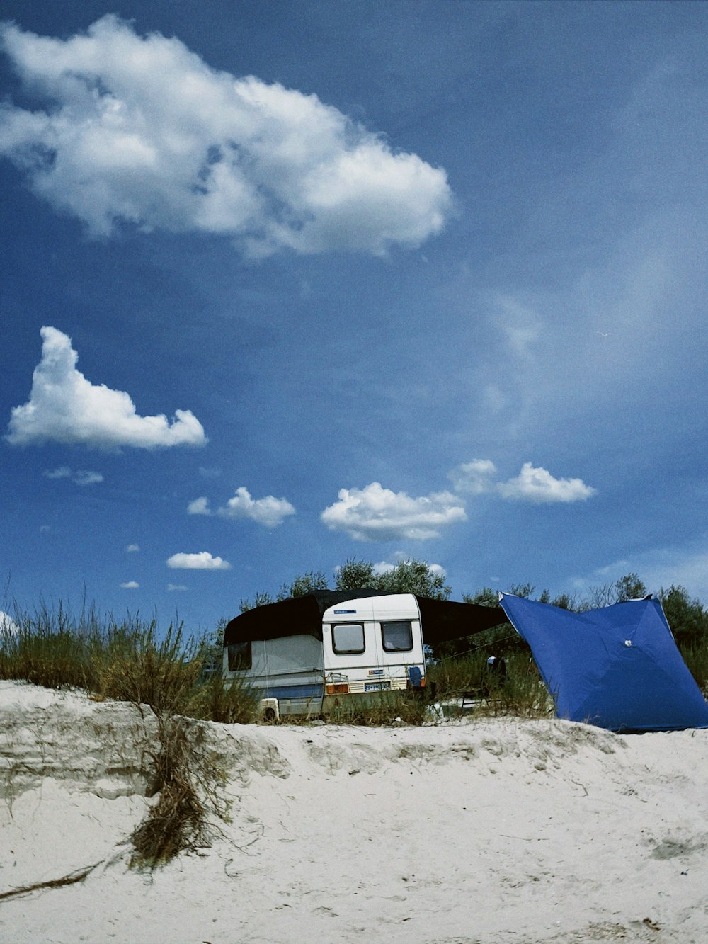 a camper is parked on the beach with a blue tarp