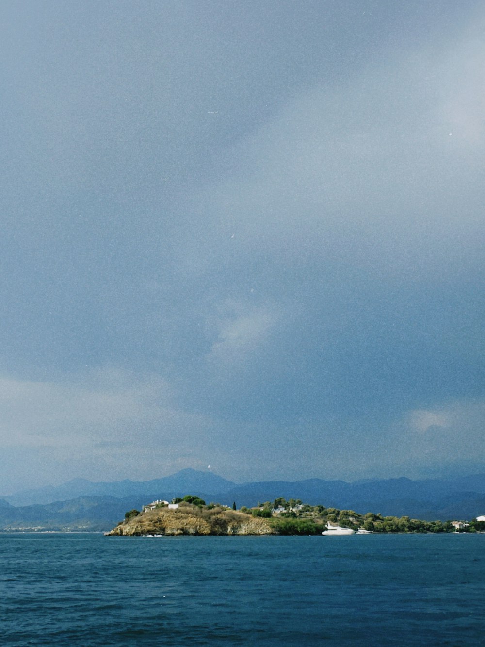 a sail boat in the water with a small island in the background