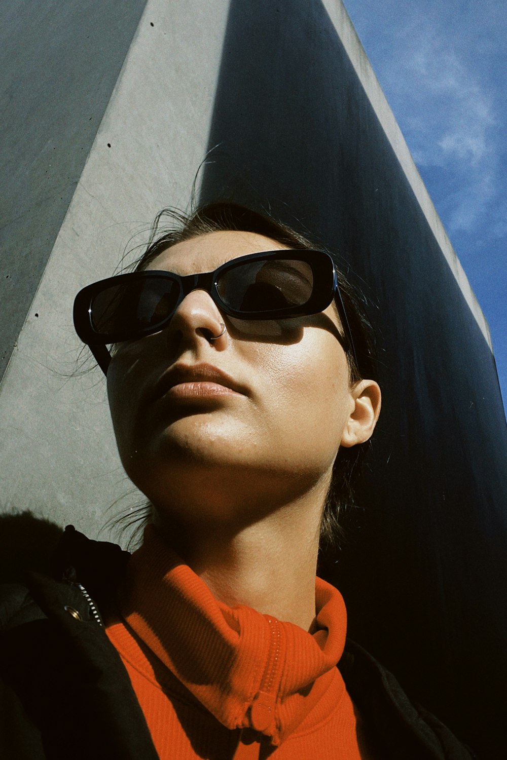 Una donna che indossa occhiali da sole in piedi di fronte a un edificio alto