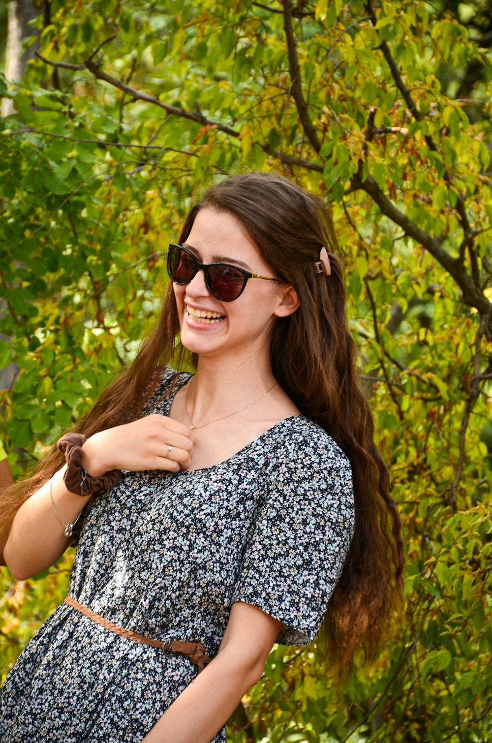 a woman in a dress and sunglasses smiling