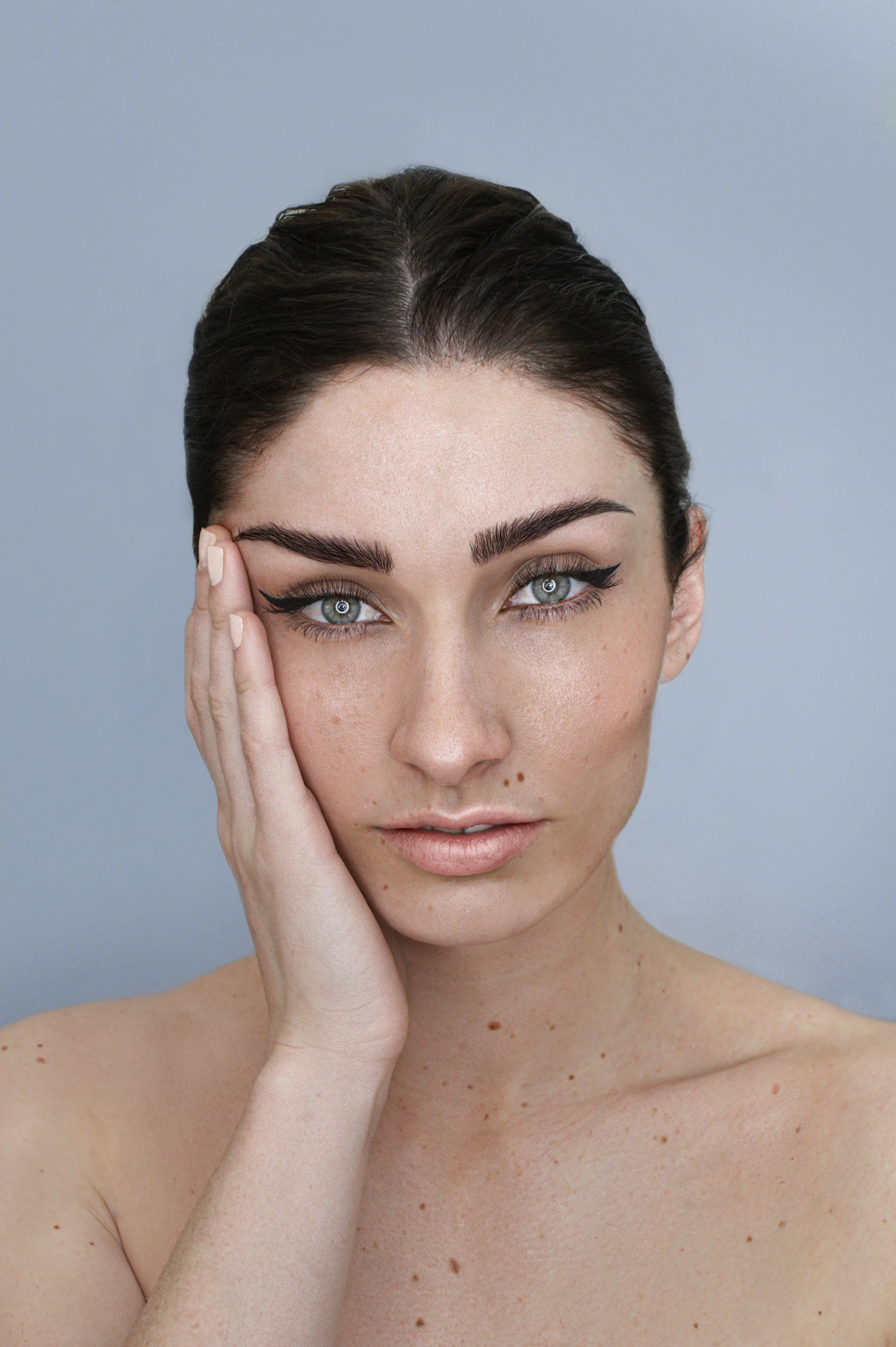 Warm editorial portrait of a woman with a hand resting near her chin and jawline in soft natural light