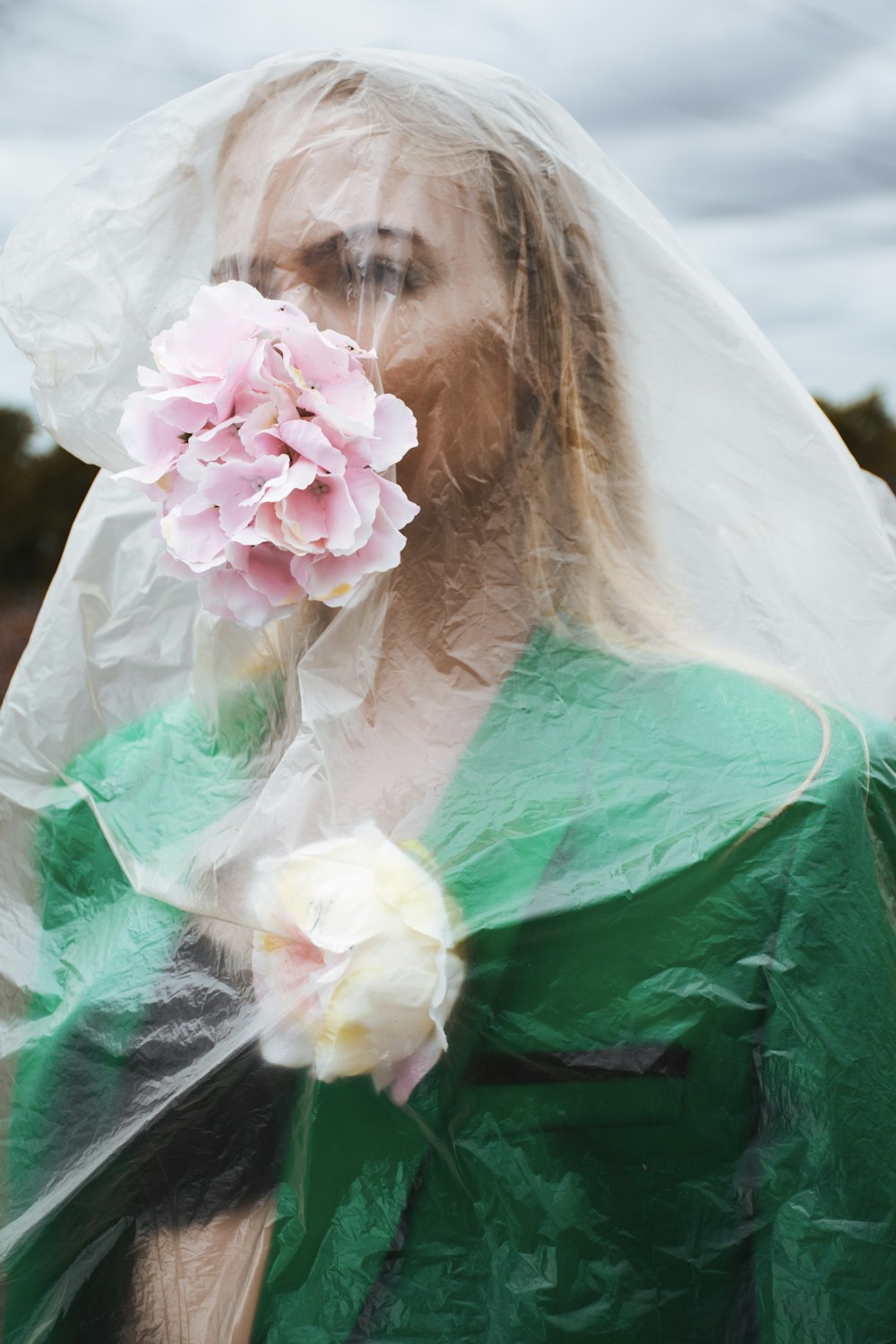 a woman in a green dress holding a pink flower