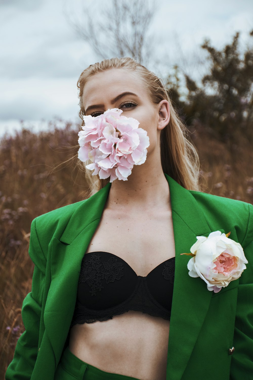 a woman in a green jacket with a flower in her mouth