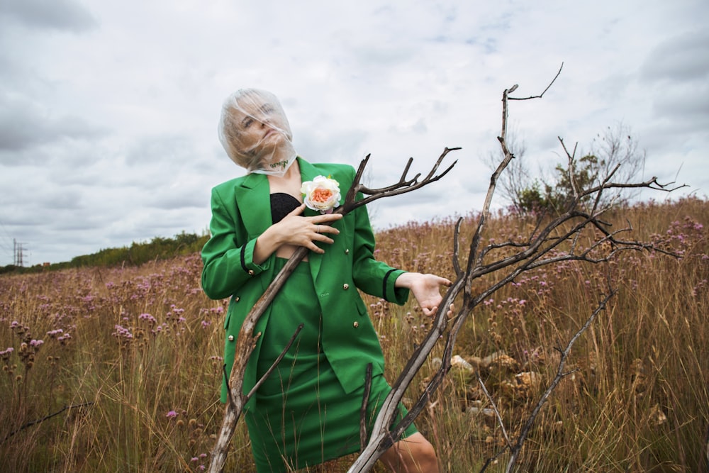 a woman standing in a field holding a flower