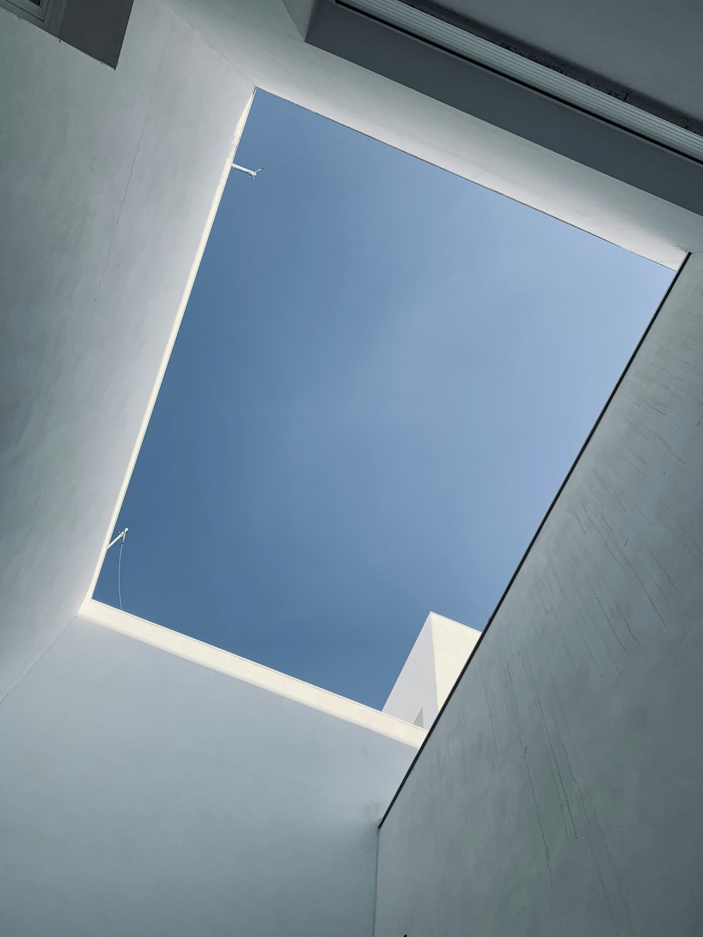 a skylight in a white room with a blue sky